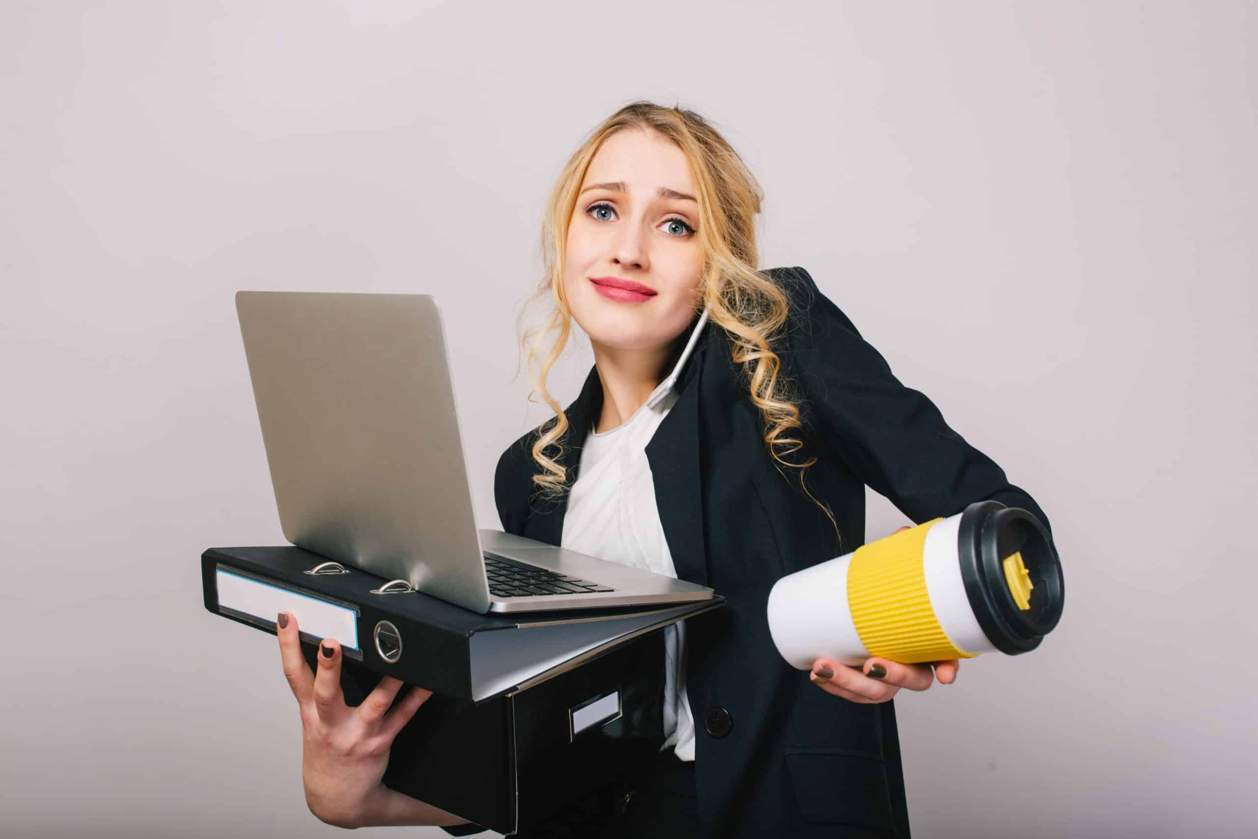 Cute blonde young office woman in white shirt, black jacket, with laptop, folder, coffee to go isolated on white background. Expressing true emotions, success, work, having fun